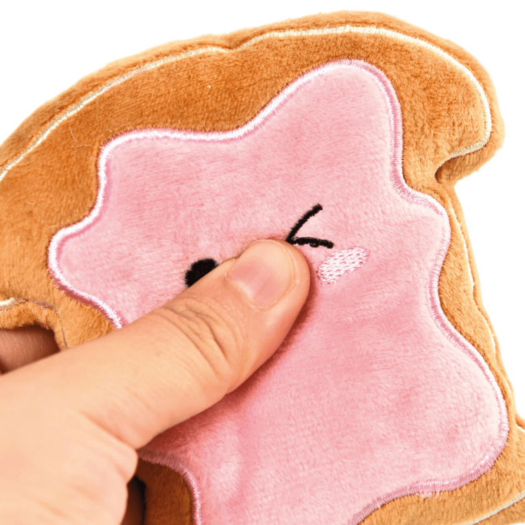 Plano detalle de la textura suave y acolchada de un juguete de peluche para perros de Premier DOG siendo presionado para mostrar su blandura en Anlú.