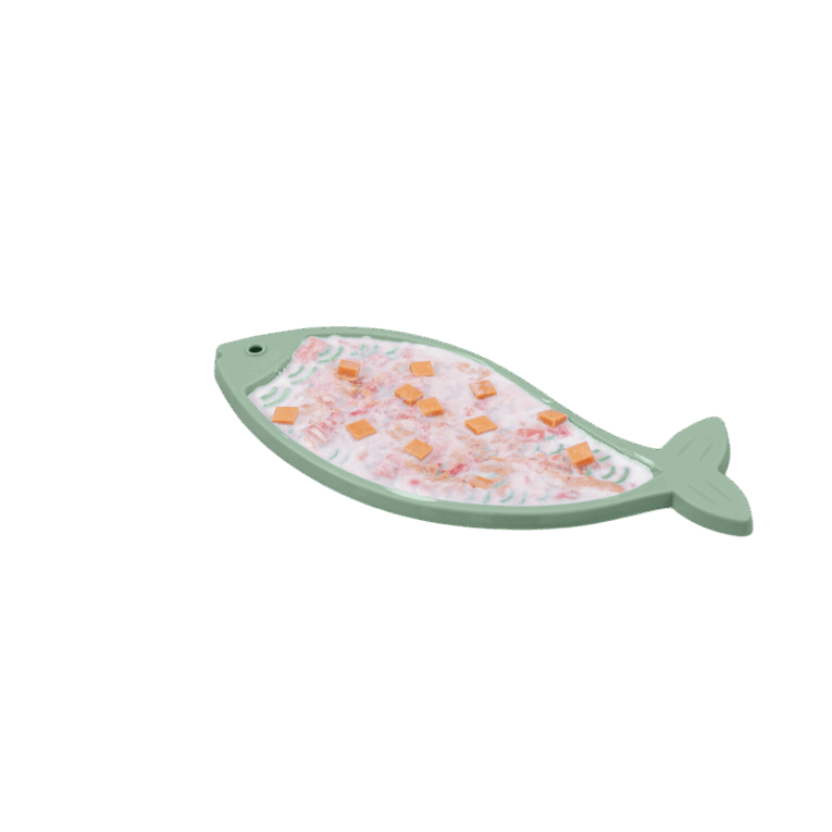 Vista cenital del mantel Trixie Lick'n'Snack de silicona con forma de pez, completamente rellenado con una mezcla de comida húmeda o yogur y trozos visibles de premios o vegetales.