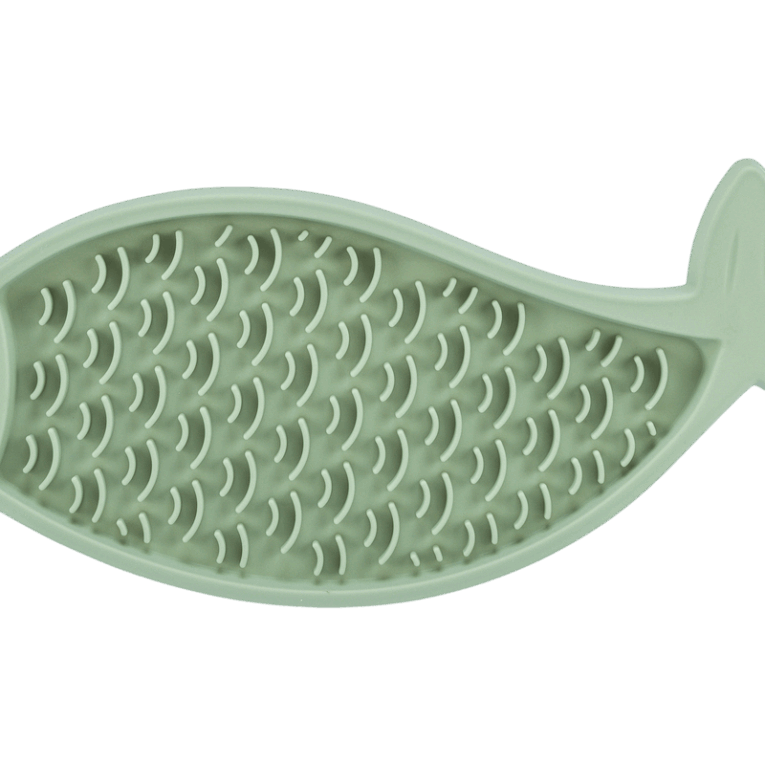Vista cenital completa del mantel Trixie Lick'n'Snack de 28cm con forma de pez. Se aprecia el patrón repetitivo de pequeñas curvas que simulan escamas en el color verde pastel.