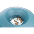 Primer plano del orificio central del comedero Trixie Rocking Bowl azul, con varias croquetas de pienso visibles en el fondo blanco. Demuestra cómo el alimento es dispensado gradualmente.