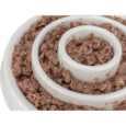 Vista de primer plano extremo del comedero slow feeding de 23cm lleno de paté de carne. El alimento húmedo se encuentra firmemente adherido a las paredes de los anillos concéntricos de plástico blanco.