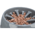 Primer plano en ángulo del comedero Slow Feeding Napf de plástico Trixie de 25cm, color gris oscuro, relleno de alimento húmedo (carne picada o paté). Los obstáculos altos en forma de rayos dividen la comida.