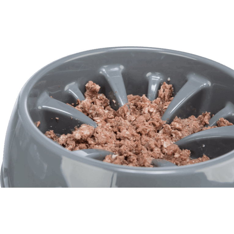 Primer plano en ángulo del comedero Slow Feeding Napf de plástico Trixie de 25cm, color gris oscuro, relleno de alimento húmedo (carne picada o paté). Los obstáculos altos en forma de rayos dividen la comida.
